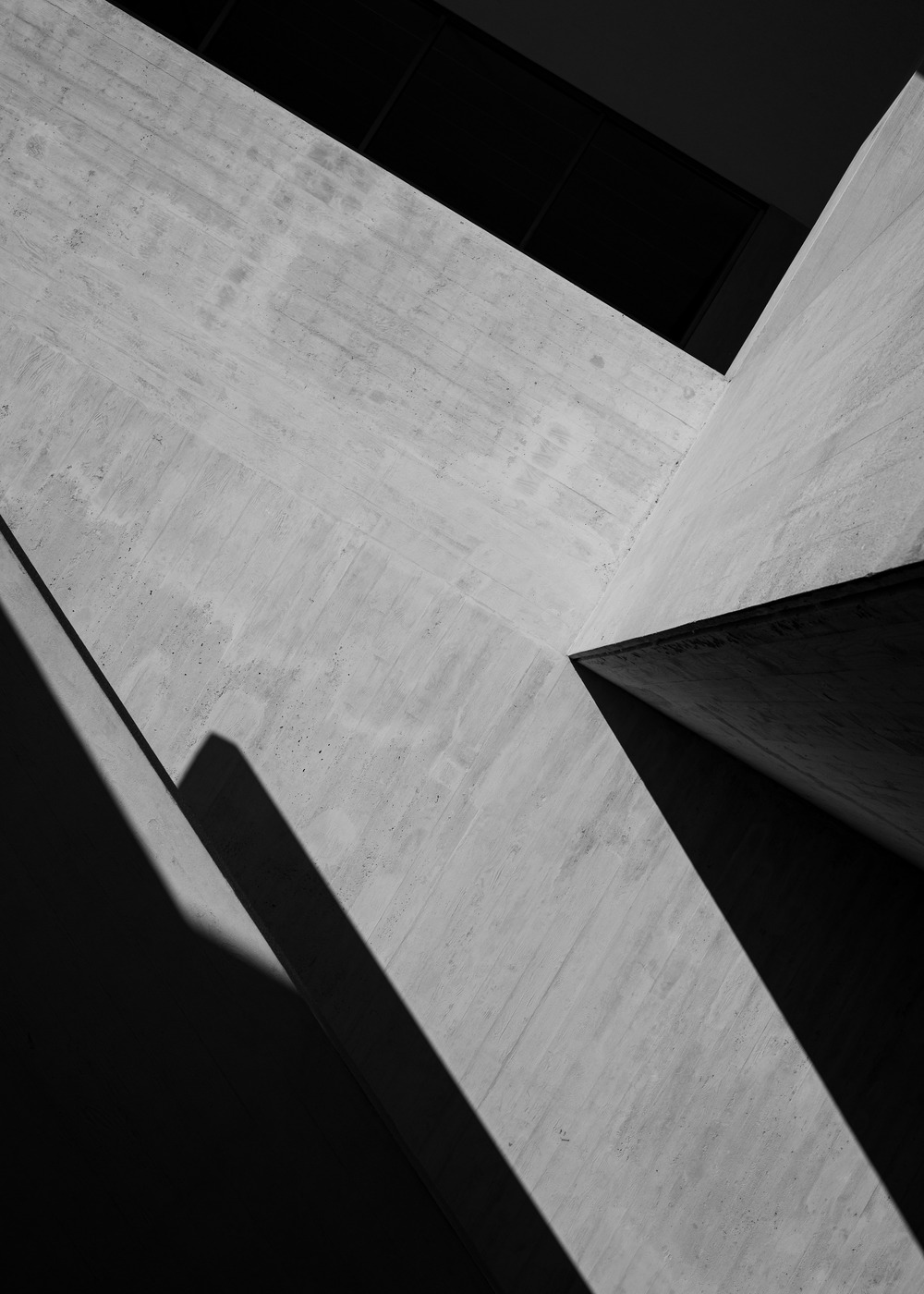 Concrete facade planes and recessed windows in deep shadow